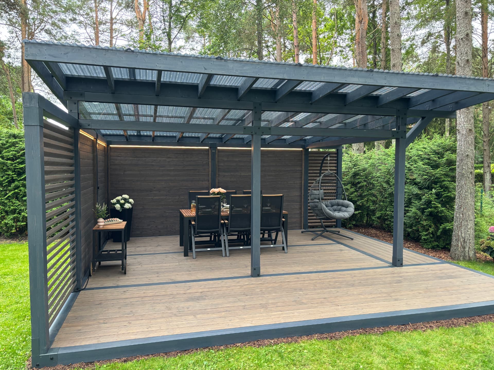 Built timber pavilion with dining and lounge areas in a garden